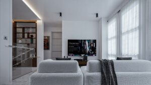 A house for sale in Ghana. A living room view of a luxury house with a very wide TV mounted on the wall directly facing the white L-shaped sofa
