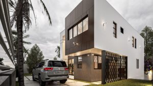 The front view of a white and brown one storey house at Regimanuel Satellite City with a Toyota Land Cruiser parked in front of the house