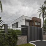 Houses For Sale in Accra with Off-Plan & Monthly Installments - A view from the front gate of a storey house. The walls are short with metal balusters that allow you to see the upper portion of the house.